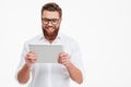 Cheerful young bearded man using tablet computer. Royalty Free Stock Photo