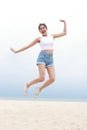 Cheerful young beautiful Asian woman having fun in white shirt and shorts jumping high on the beach. Royalty Free Stock Photo