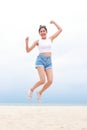 Cheerful young beautiful Asian woman having fun in white shirt and shorts jumping high on the beach. Royalty Free Stock Photo