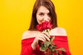 Cheerful young beautiful woman holding a red rose and looking a the camera over yellow background Royalty Free Stock Photo