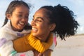 Cheerful young biracial woman looking at daughter while giving her piggyback ride during sunset Royalty Free Stock Photo