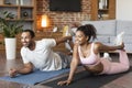 Cheerful young black family in sportswear doing leg stretching exercises on mat on floor, enjoy workout Royalty Free Stock Photo