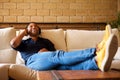 Cheerful young black man lying on sofa with headphones and listening to music Royalty Free Stock Photo