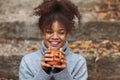 Cheerful young black woman with sparkling glitter makeup sitting outside with cup of tea Royalty Free Stock Photo