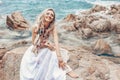 Cheerful young boho style woman in white dress on stone beach Royalty Free Stock Photo