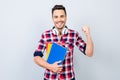 Cheerful young brunet nerdy student with stubble is standing wit