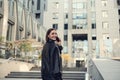 Cheerful young brunette woman talking on mobile phone smiling toothy smile looking over shoulder at camera climbing stairs to Royalty Free Stock Photo