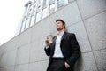 Cheerful young businesman drinking coffee outdoors