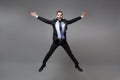 Cheerful young business man in black suit shirt tie posing isolated on grey background. Achievement career wealth