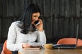 Cheerful young business woman standing in modern office talking on her mobile phone. Beautiful female model using cell phone Royalty Free Stock Photo