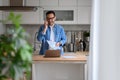 Cheerful young businessman holding document and talking over smart phone while standing in kitchen Royalty Free Stock Photo