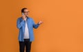 Cheerful young businessman looking away and discussing over mobile phone against orange background Royalty Free Stock Photo