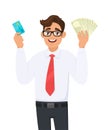 Cheerful young businessman showing credit, debit, ATM card. Person holding cash, money, currency notes in hand. Male character. Royalty Free Stock Photo