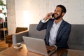 Cheerful young businessman sitting on sofa and talking on cellphone in office. Royalty Free Stock Photo