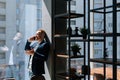 Cheerful young businessman wearing fashion suit is talking on mobile phone in modern office room Royalty Free Stock Photo