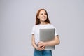 Cheerful young businesswoman holding laptop computer and looking away on  gray background. Royalty Free Stock Photo