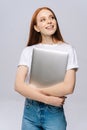 Cheerful young businesswoman holding laptop computer and looking away on isolated gray background. Royalty Free Stock Photo