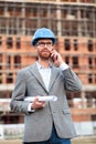 Young civil engineer or businessman standing in front of a construction site and talking on the phone Royalty Free Stock Photo