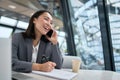 Cheerful young chinese business woman talking on phone working in office. Royalty Free Stock Photo