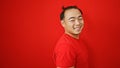 Cheerful young chinese man, confident and laughing, standing over isolated red background, exuding happiness and positive energy