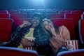 Cheerful young couple, attractive man and woman smiling, sitting at the cinema, watching a movie and eating popcorn Royalty Free Stock Photo