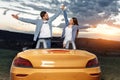 Cheerful young couple going on a long drive in a convertible car. Freedom, travel and love concept. Royalty Free Stock Photo