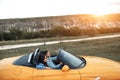 Cheerful young couple going on a long drive in a convertible car. Freedom, travel and love concept. Royalty Free Stock Photo