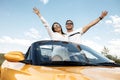Cheerful young couple going on a long drive in a convertible car. Freedom, travel and love concept. Royalty Free Stock Photo