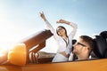 Cheerful young couple going on a long drive in a convertible car on the sunset. Freedom, travel and love concept. Royalty Free Stock Photo