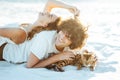 Cheerful young couple having fun on the beach with their bengal cat