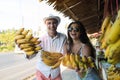 Cheerful Young Couple Holding Bananas Bunch On Street Market Happy Smiling Tourists In Asian Fruits Bazaar Royalty Free Stock Photo