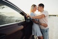 Cheerful Young Couple Hugging Near the Car, Tattooed Woman and Caucasian Man Enjoying Road Trip at Sunset Royalty Free Stock Photo