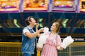 Cheerful young couple in love resting in an amusement Park and feed each other cotton candy. Love day, Royalty Free Stock Photo