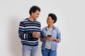 Cheerful young couple messaging over smart phones and looking at each other on white background Royalty Free Stock Photo