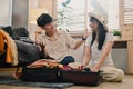 Cheerful young couple packing clothes in the suitcase, preparing for vacation trip in living room Royalty Free Stock Photo