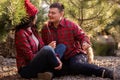 Cheerful young couple in red checkered shirts hold festive sparklers in hands. Christmas tree market Royalty Free Stock Photo
