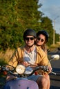 Cheerful young couple smiling at camera while riding a retro scooter and having fun outside the city Royalty Free Stock Photo