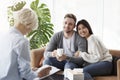 Cheerful Young Couple Talking With Family Psychologist In Office