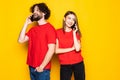 Cheerful young couple talking on mobile phones over yellow background Royalty Free Stock Photo