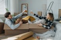 Cheerful young couple in their new apartment, sitting in boxes and clinking glasses. Conception of moving.