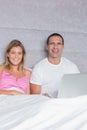 Cheerful young couple using their laptop together in bed Royalty Free Stock Photo