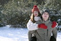 Cheerful young couple in winter in forest. Guy rolls the girl on his back Royalty Free Stock Photo