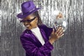 Cheerful young dark-skinned woman with shiny mirror disco ball in her hand on silver background. Royalty Free Stock Photo