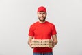 Cheerful young deliveryman holding pizza boxes while isolated on white studio background