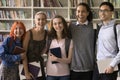 Cheerful young diverse student girls and guys posing in library Royalty Free Stock Photo