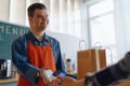 Cheerful young Down Syndrome waiter taking contactless smartphone payment from costumer in take away restaurant. Royalty Free Stock Photo