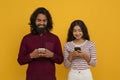 Cheerful young eastern couple with smartphones in hands Royalty Free Stock Photo