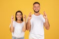 Cheerful young european man and woman in white t-shirts with crossed fingers hoping or wishing Royalty Free Stock Photo