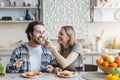 Cheerful young european woman feeds her husband of spaghetti with vegetables or pasta in minimalist kitchen Royalty Free Stock Photo