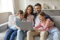 Cheerful young family with kids having fun with laptop at home Royalty Free Stock Photo